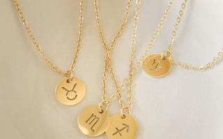 Gold monogramed circular pendants laying in a white bowl